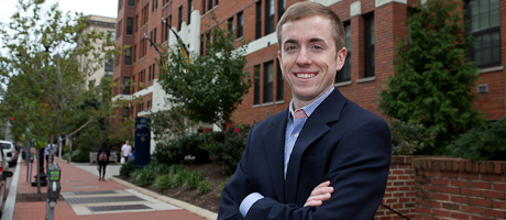 Matthew Galewski stands in front of Thurston Hall entrance with arms crossed smiling