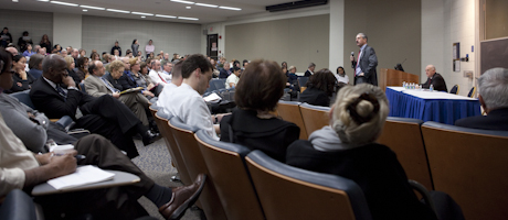 Steve Lerman on microphone in front of room as audience looks on