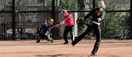 Elana Myers as catcher, and Luke Russert at bat with Jennie Finch pitching during softball game
