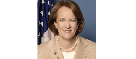 Karen Mills smiles with American flag in background