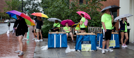 students in move in t shirts under umbrellas sitting and standing outside of residence hall
