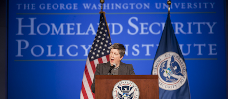 Janet Napolitano delivers speech at a DHS podium with American and Department of Homeland Security flags behind her