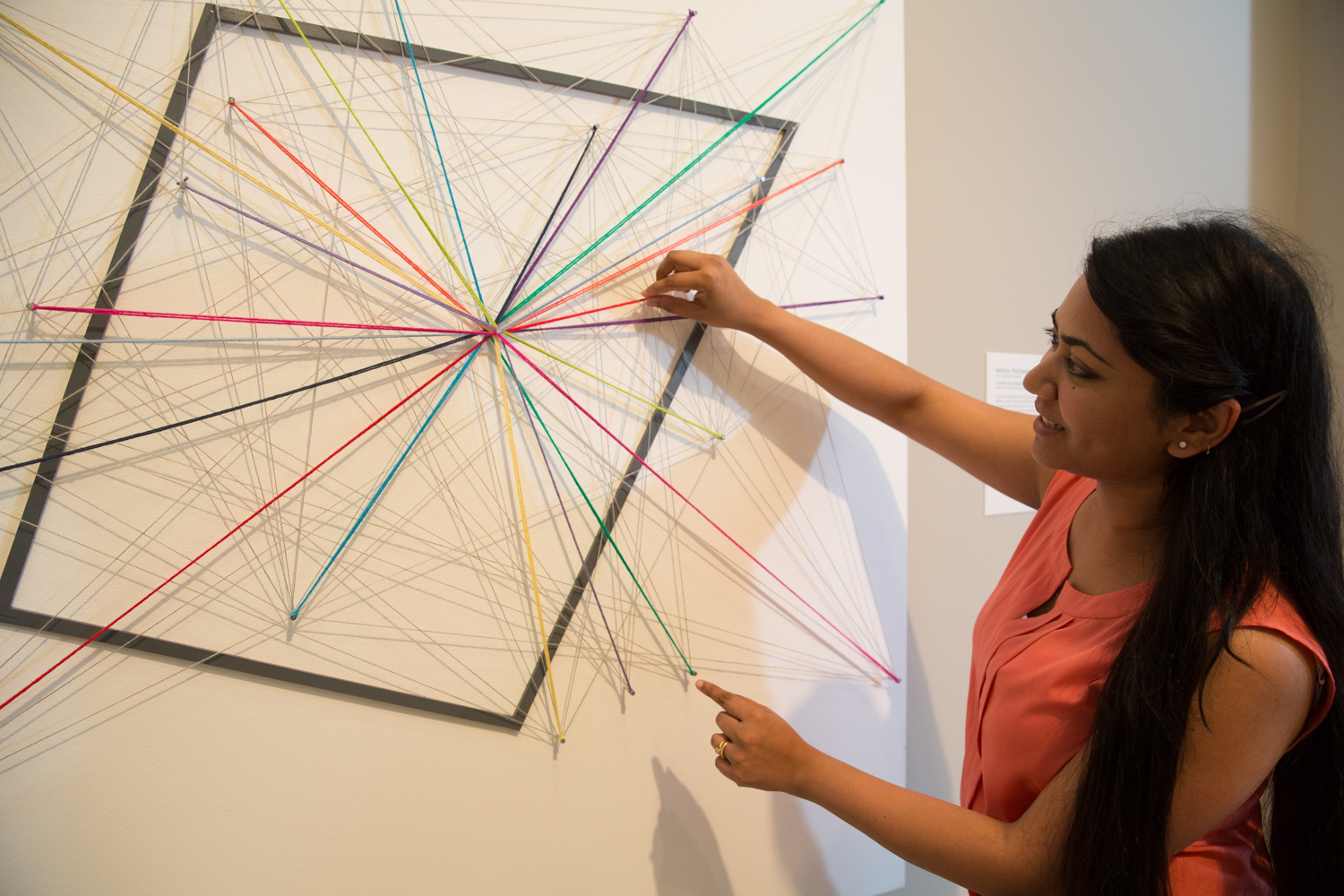 Senior Neha Pathare, next to her abstract, mixed media art piece for Corcoran's NEXT Exhibit.