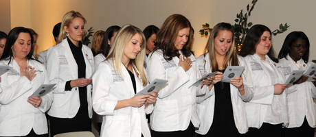 Members of the School of Nursing’s first undergraduate class holding papers and received baccalaureate pins, 
