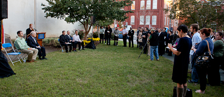 students stand at a memorial service on grass supporting each other 