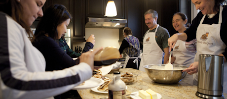 Lori and Steve Lerman serving pancakes to students while wearing aprons
