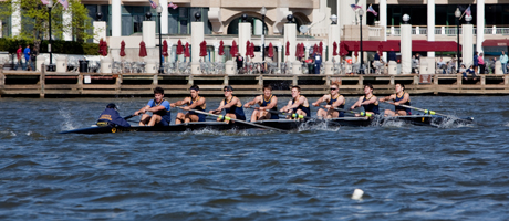 University rowing team rows in boat on Potomac River in front of Washington Harbour