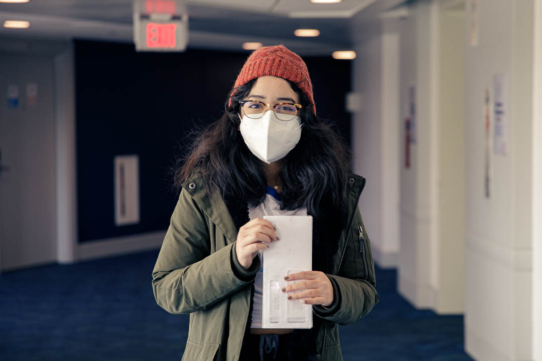 Alejandra Paredes wearing a mask and holding a stack of mail