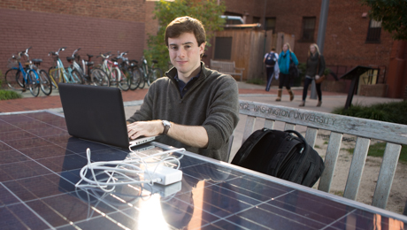 Ben Pryde sits at Solar Table with laptop smiling