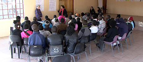 seated students watch two actors in front of room