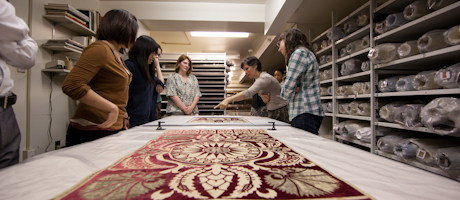 students look at textile while professor points at material