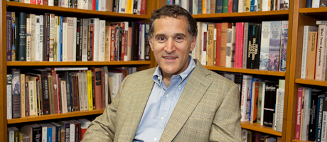 Tyler Anbinder smiles with stacks of books in background
