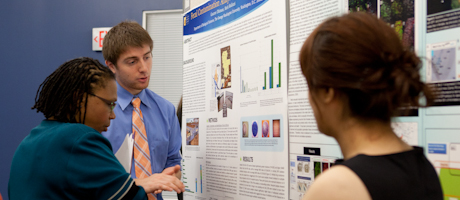 student presenting research board at symposium