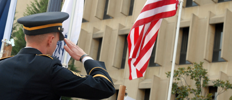 male in military uniform salutes American flag