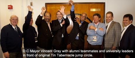 Vincent Gray with members of the university community raising arms in front of original Tin Tabernacle jump circle