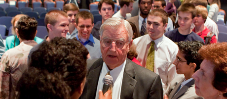 Walter Mondale speaks in to microphone while surrounded by students