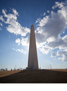 Washington Monument on a sunny day with large white clouds in the sky 
