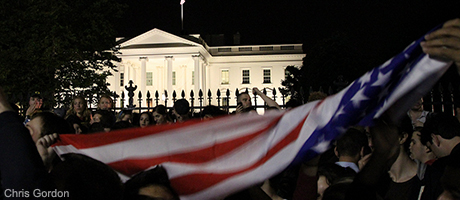 White House in evening with crowds and American flags waving