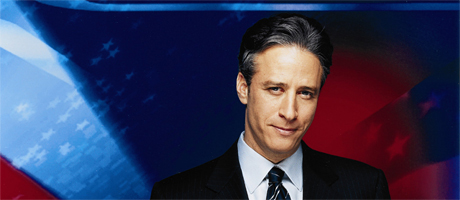 Jon Stewart in front of red, white and blue banner