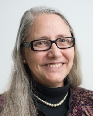 Engineering Professor Emerita W. M. Kim Roddis, smiling, white hair, black glasses, black turtleneck with string of pearls