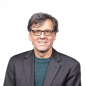 Peter Loge headshot. White man with grey hair, glasses in grey jacket and green shirt.