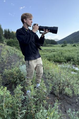 Senior Andrew McCabe with camera standing in field