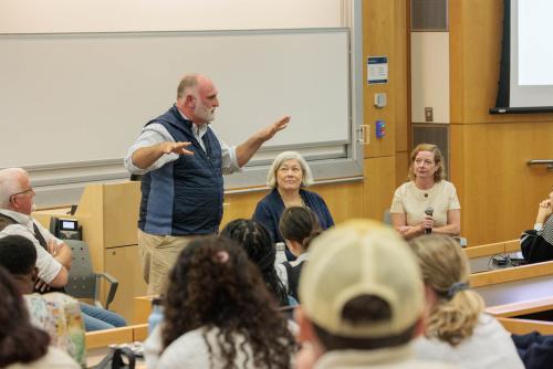 Jose Andres speaking to a classroom standing in a vest with (on this right) Robert Eggers and (on hits left) President Granberg and Bio Professor Tara Scully