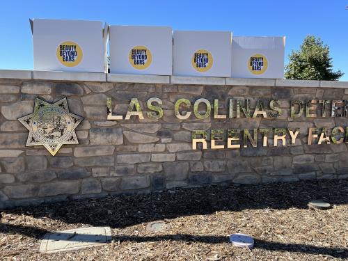 4 whites boxes with "Beauty Beyond Bars" imprints on top of a stone wall that reads "Las Colinas Detention Facility."
