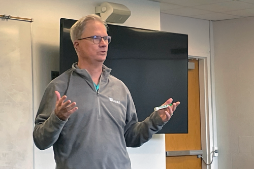Chemistry Professor Holden Thorp teaching a class, wearing a grey pullover, holding a black major marker.