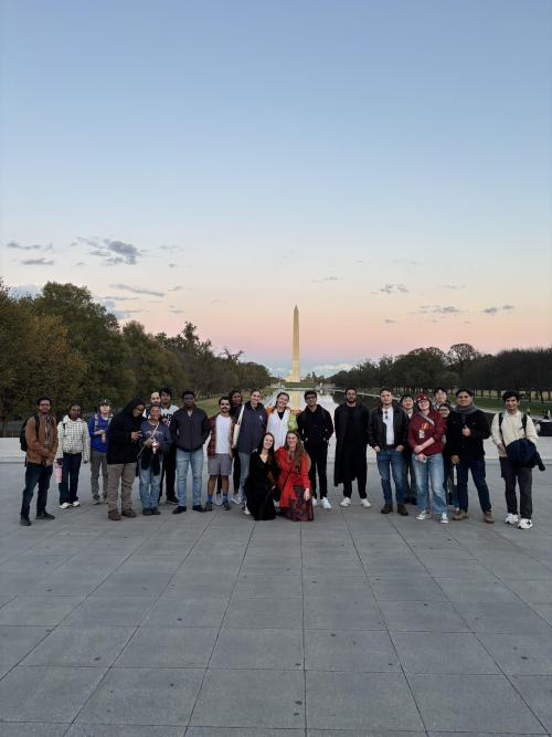 Graduate students, pictured with the Washington Monument in the background, toured D.C. monuments at Halloween.