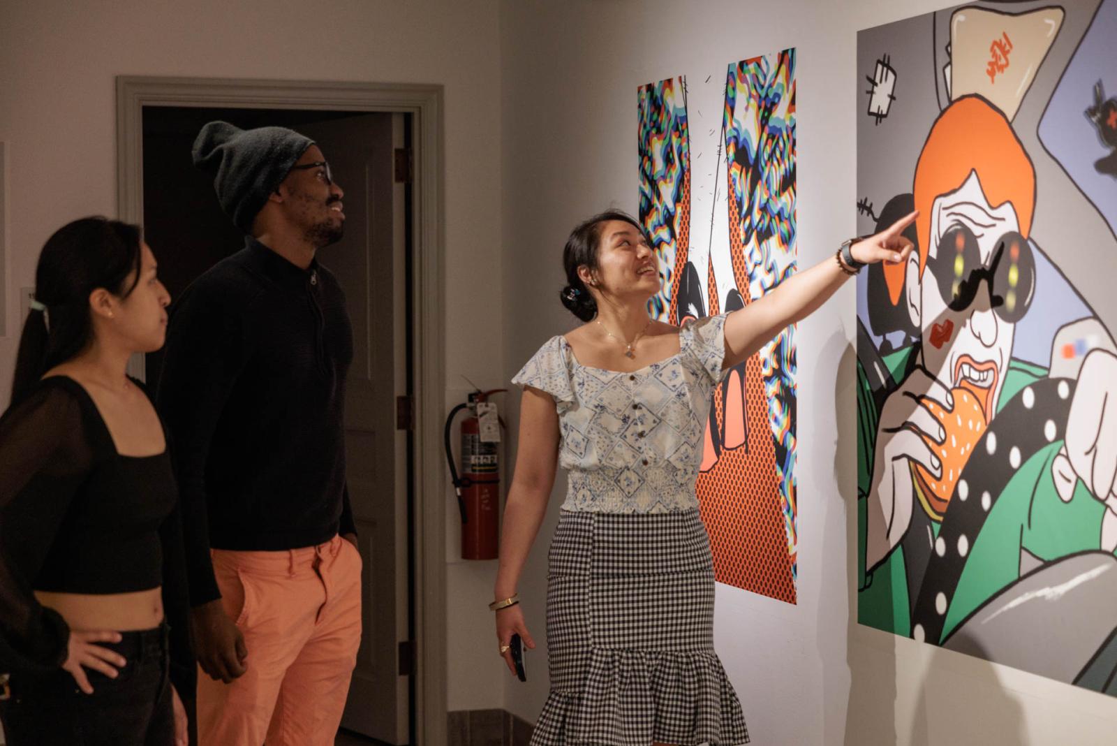 Three people discuss a work of art at NEXT