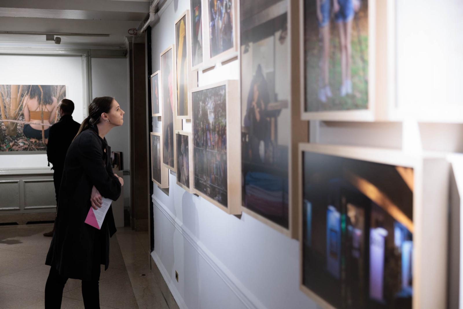 Two people study artworks on display at NEXT