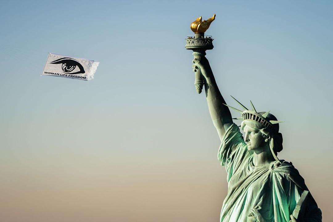 “Reflection of Woman” by Mahvash Mostala, New York, 2022. Statue of Liberty with floating kite with image of eye and words "Woman Life Freedom"