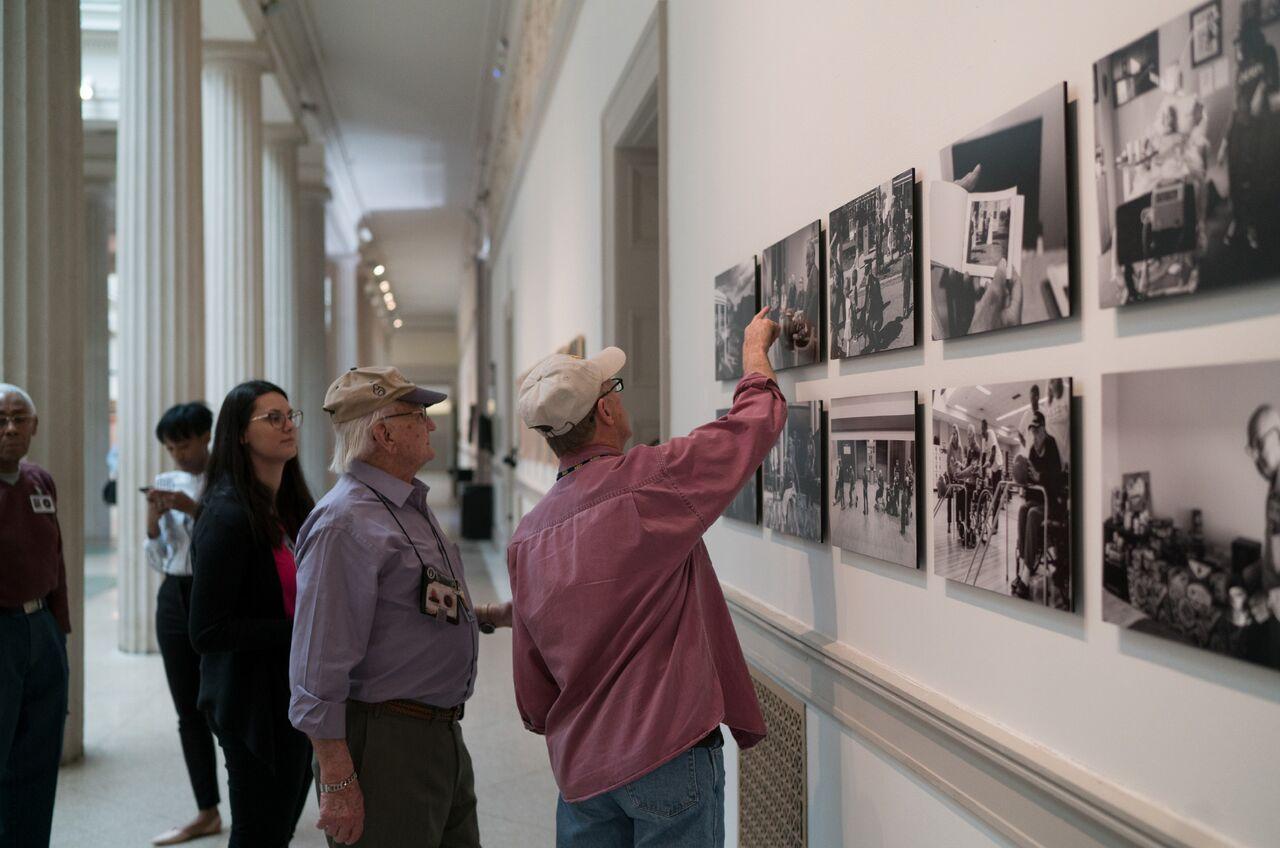 men looking at armed forces photography on walls