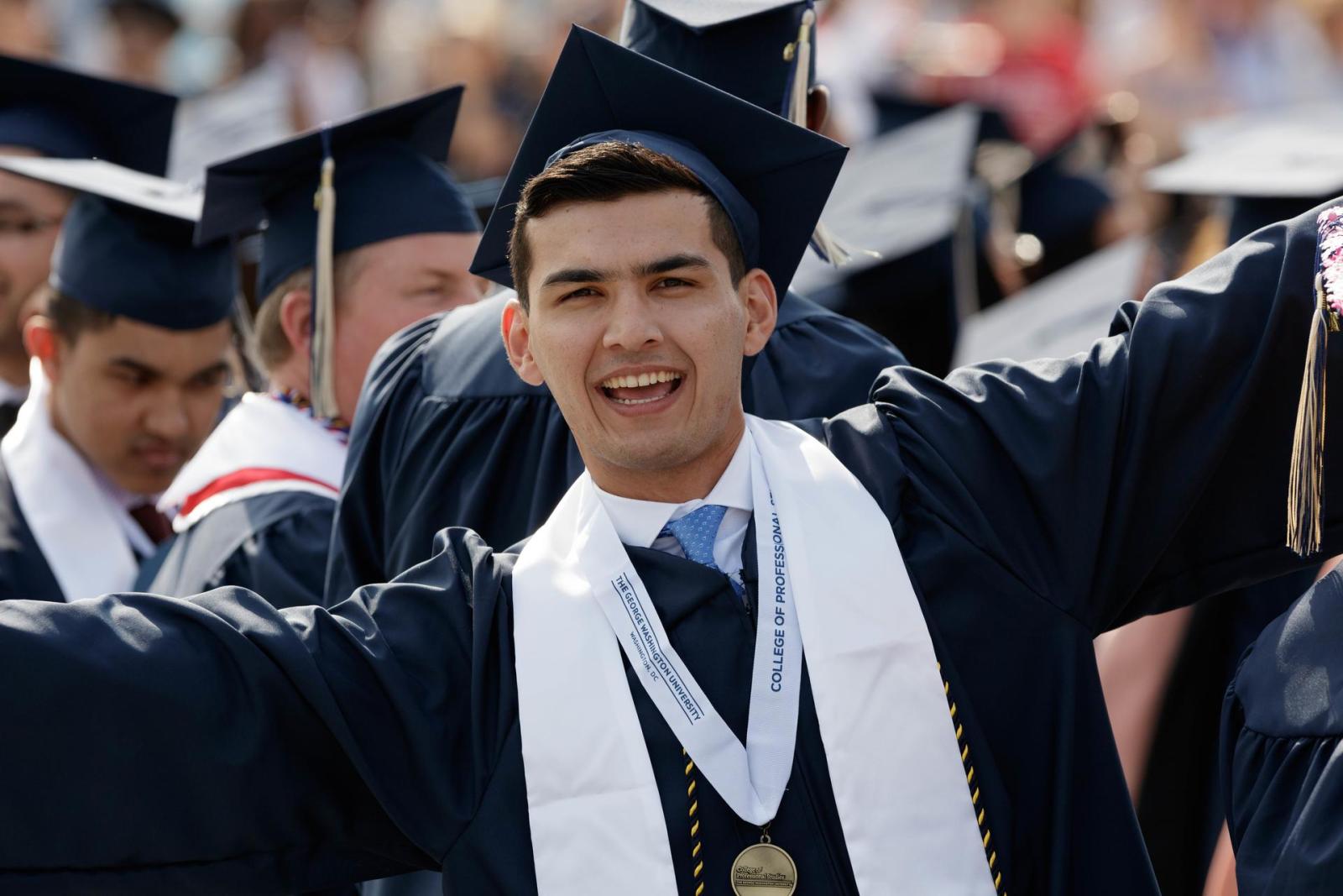 graduate smiling with arms outstretched