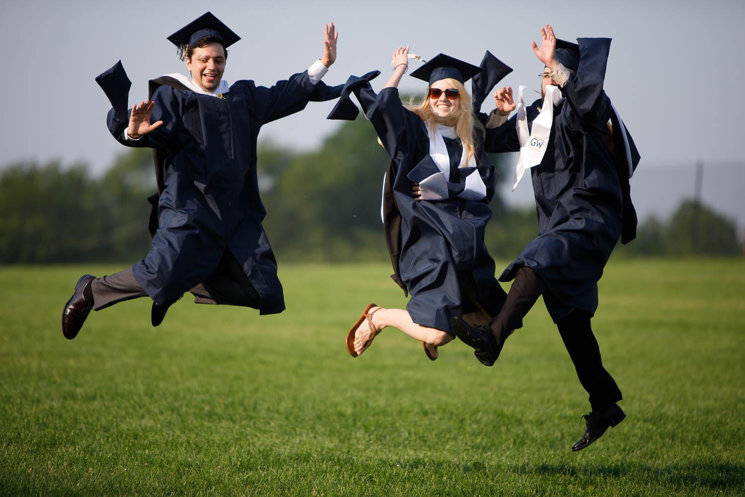 three students in regalia jumping