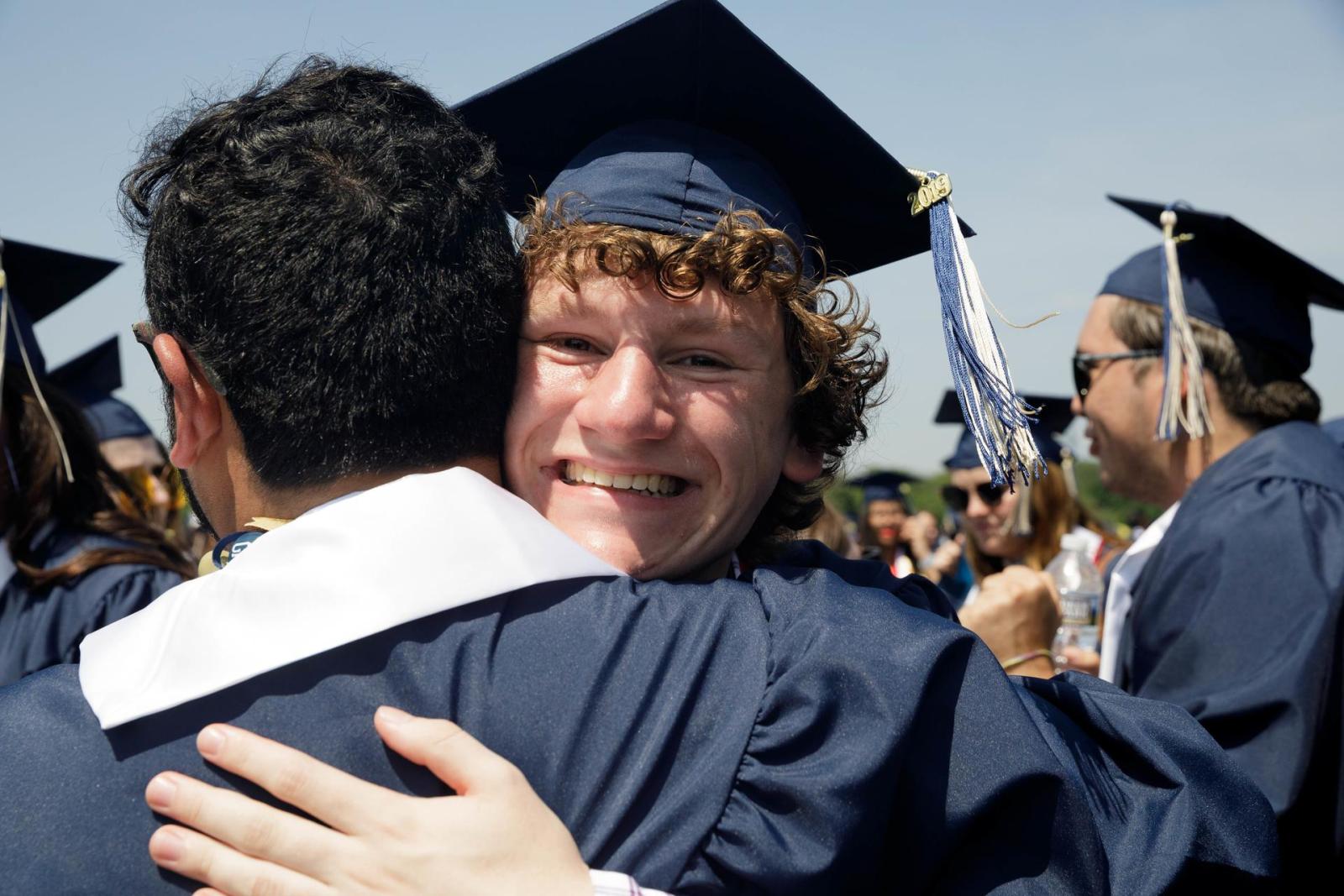students embracing in commencement attire