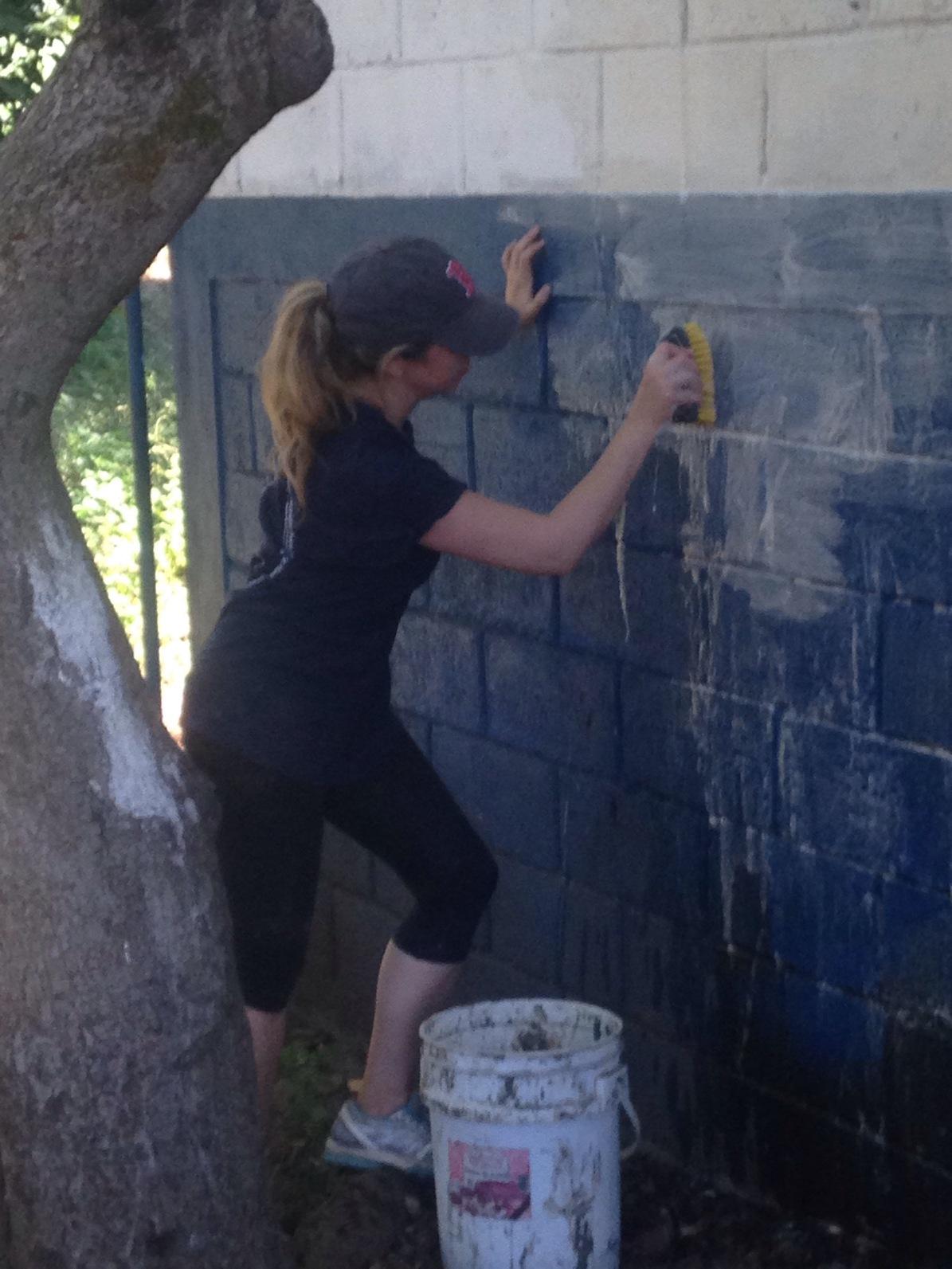 A student cleans a wall of the El Manzano Uno elementary school before painting it.