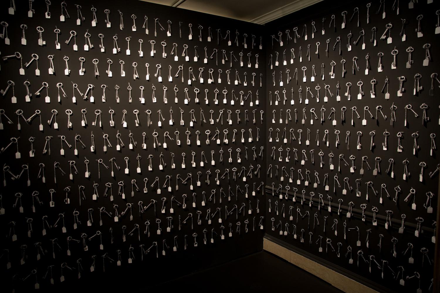 A black-painted room with keys nailed all over the walls.