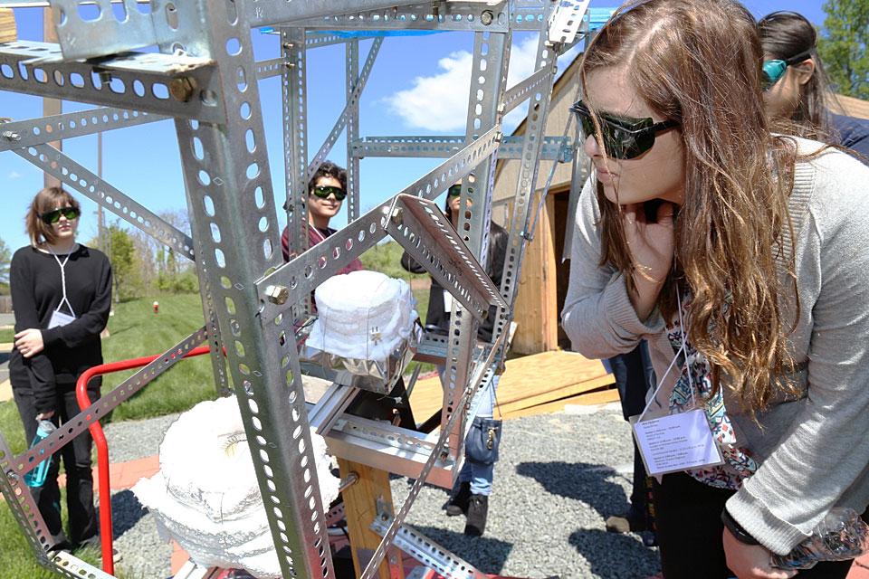 A female student closely inspects a metal structure at STEM Day .