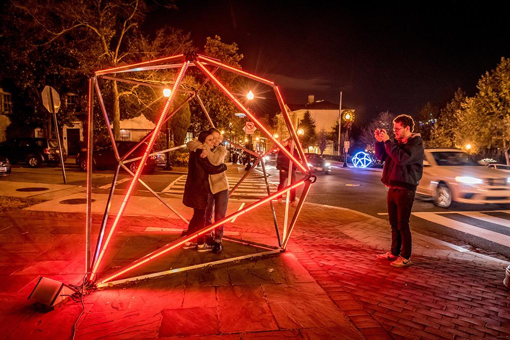 Two people getting photo taken inside diamond-shaped light installation. From Georgetown GLOW