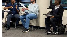 Mohanad Alsaid and Dex Burns sit in class next to professor Ramien R. Pierre. 