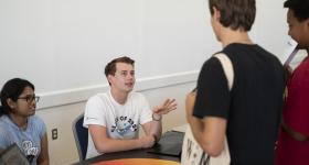 A male student talks to two other students at Org Fair Friday