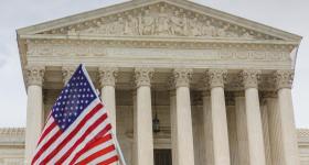 Facade of the U.S. Supreme Court with American flags in foreground 