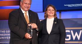 U.S. Navy Secretary Carlos Del Toro accepts the GSPM Alumni Lifetime Achievement Award presented by CPS Dean Liesl Riddle. 