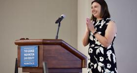 Elizabeth Vaquera, associate professor of sociology and public policy and public administration, in a black & white dress at a GWU lectern
