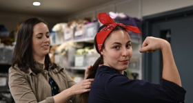 Costumer Emily Vallozzi helps a student with a Rosie the Riveter costume