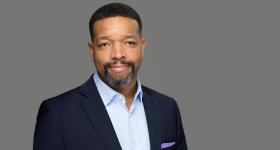 Lorenzo Norris, a man with a beard and short hair, in a navy blazer and blue shirt.. 