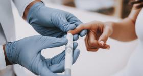 Doctor testing a person's blood glucose level
