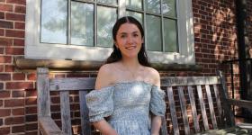 Junior political science and accounting major Emily-Anne Santiago  in a blue dress sitting on a bench